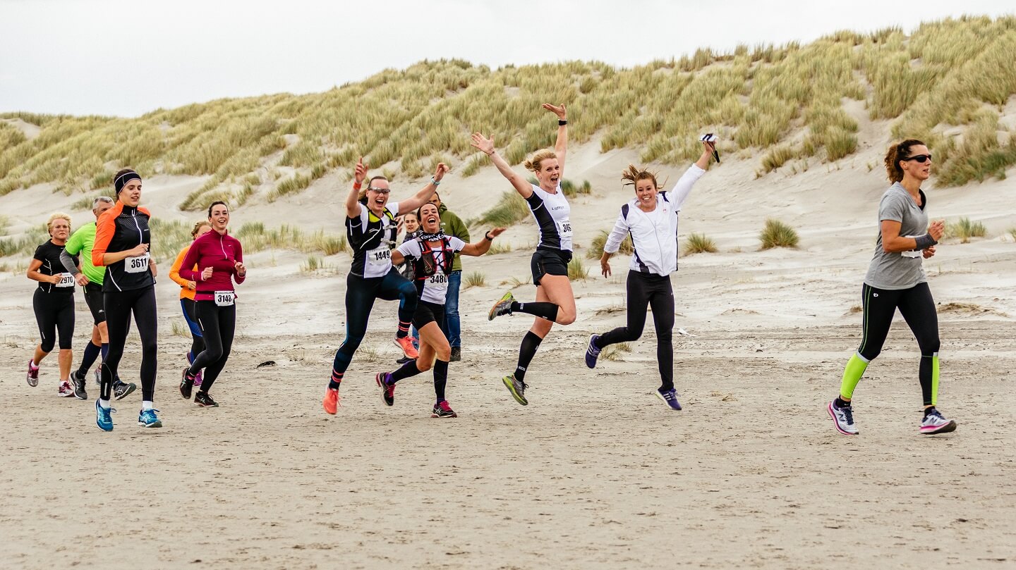 Berenloopsters van Team Anita springen een gat in de lucht op het strand tijdens de Berenloop 2017.