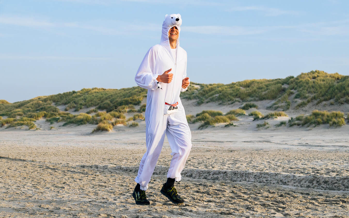 Berenloper in ijsberenpak loopt op het strand tijdens de Berenloop Terschelling.